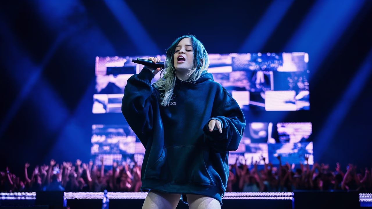 Billie Eilish performing live at OVO Hydro in Glasgow during her Hit Me Hard and Soft Tour on July 7, 2025, under moody blue stage lighting.