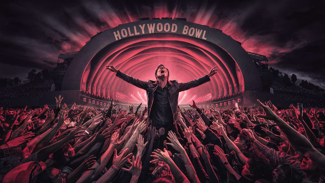 My Chemical Romance performing live at the Hollywood Bowl, with Gerard Way engaging the massive crowd under dramatic red and black stage lights and the iconic shell of the venue in the background.